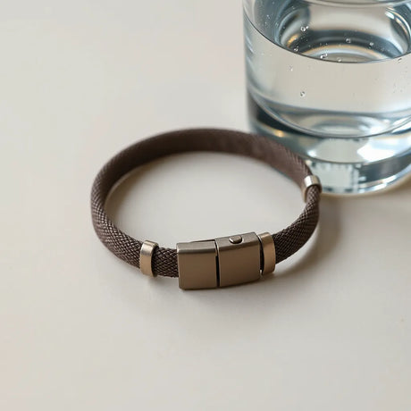 Wasserdichtes Armband mit sichtbaren Wassertropfen neben einem Glas mit Wasser
