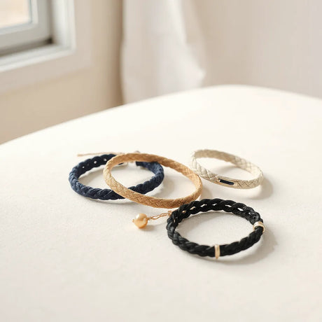 Mehrere minimalistische Stoffarmbänder in gedeckten Farben auf neutralem Untergrund