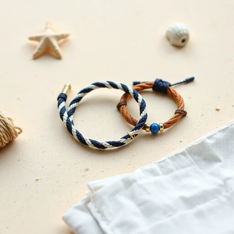 Mehrere marineblaue und weiße Armbänder mit Seil- und Charm-Details auf hellem Untergrund